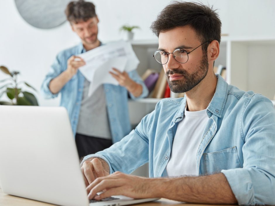 Consultor SEO con camisa azul en frente de un ordenador portátil